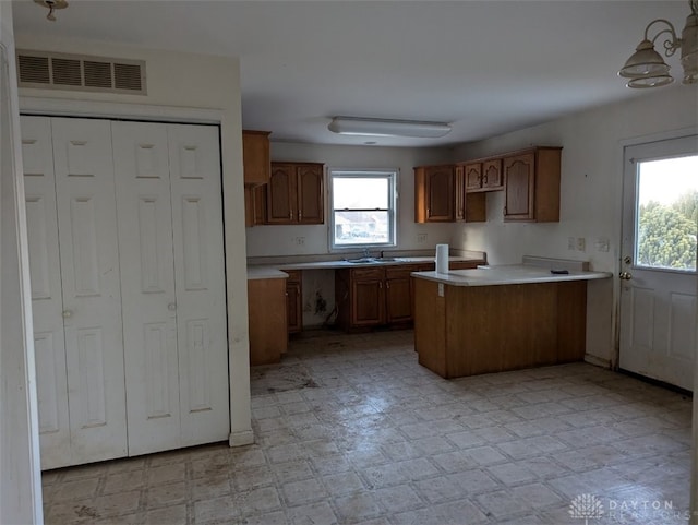 kitchen with visible vents, a sink, brown cabinetry, light countertops, and light floors