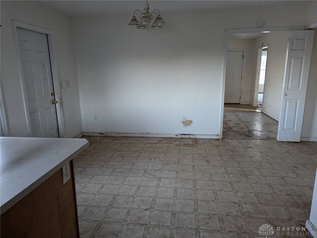 unfurnished dining area with a notable chandelier, baseboards, and light floors