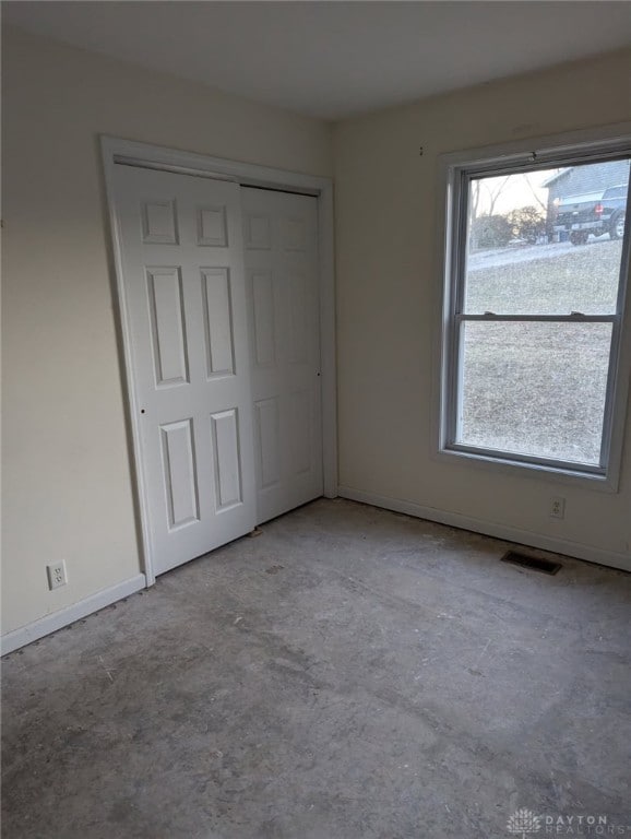 unfurnished bedroom featuring visible vents, baseboards, concrete floors, and a closet