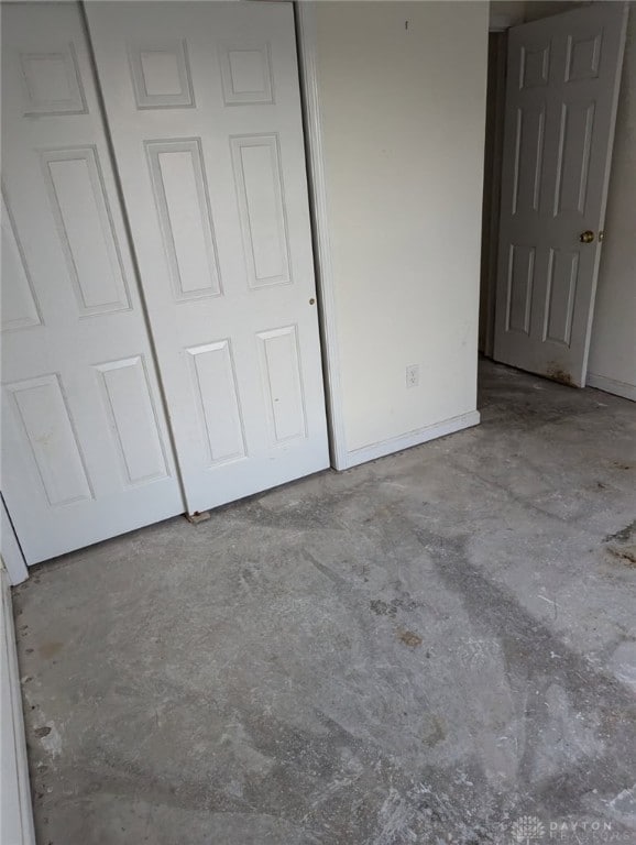 unfurnished bedroom featuring a closet, baseboards, and concrete floors