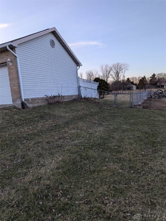 view of property exterior with a garage, a yard, fence, and brick siding