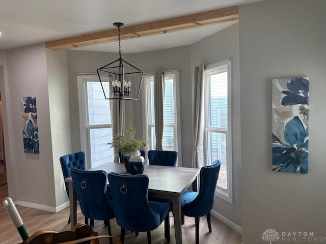 dining room featuring beam ceiling, light wood-style flooring, a notable chandelier, and baseboards