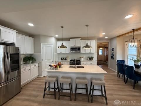 kitchen featuring light wood finished floors, appliances with stainless steel finishes, a breakfast bar, and a sink