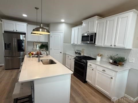 kitchen featuring wood finished floors, white cabinetry, stainless steel appliances, and a sink