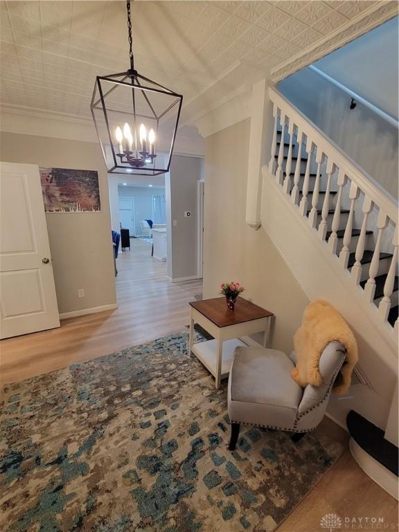 hallway featuring wood finished floors, baseboards, an ornate ceiling, ornamental molding, and stairs