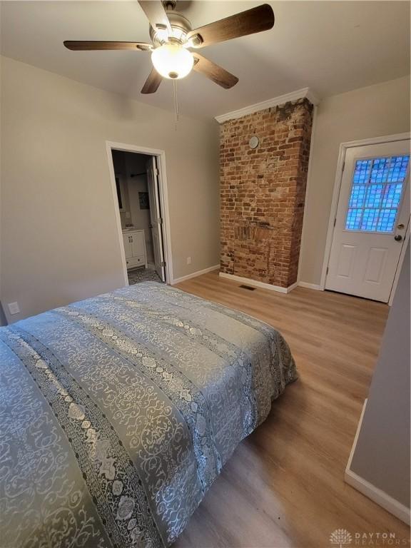 bedroom with ceiling fan, baseboards, wood finished floors, and brick wall