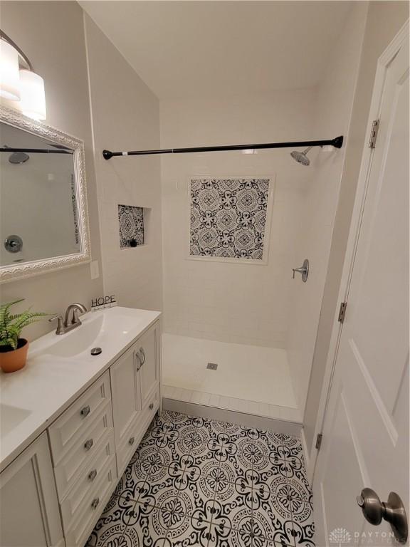 bathroom with a sink, a shower, double vanity, and tile patterned flooring