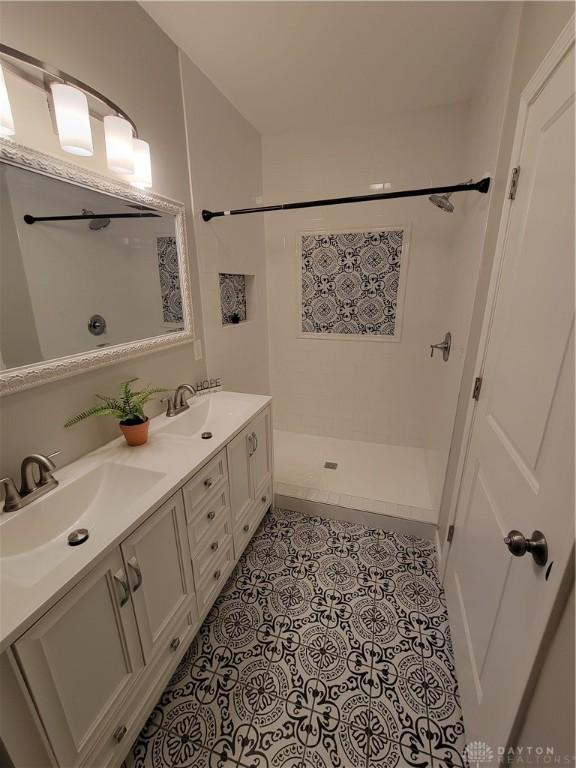 full bath featuring a sink, walk in shower, double vanity, and tile patterned flooring