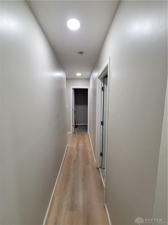 hallway featuring light wood-type flooring and baseboards