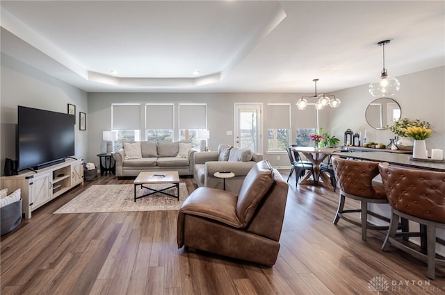 living room featuring dark wood finished floors, a raised ceiling, and a chandelier