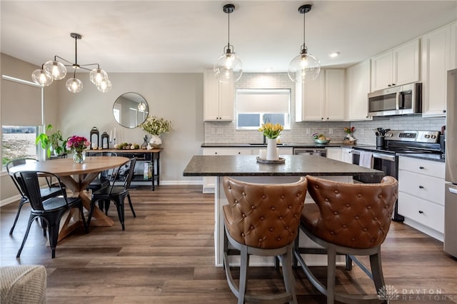 kitchen with stainless steel appliances, dark countertops, a center island, and decorative backsplash