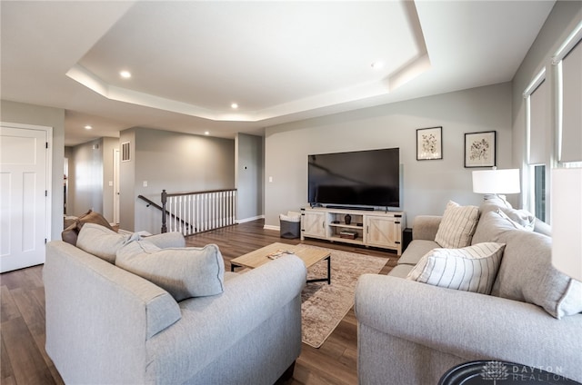 living room with recessed lighting, a tray ceiling, baseboards, and dark wood-style flooring