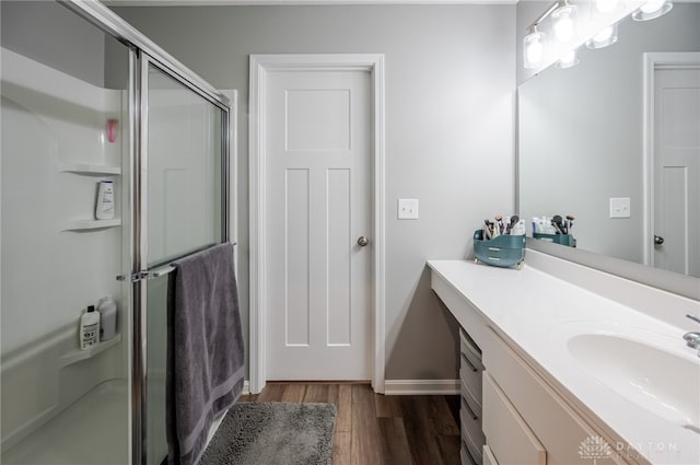 bathroom featuring vanity, wood finished floors, a stall shower, and baseboards