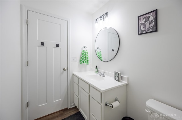 half bathroom with toilet, wood finished floors, and vanity