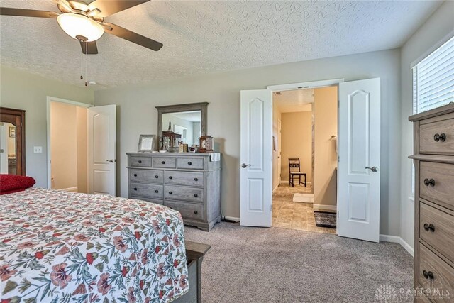 bedroom featuring light carpet, a textured ceiling, baseboards, and a ceiling fan