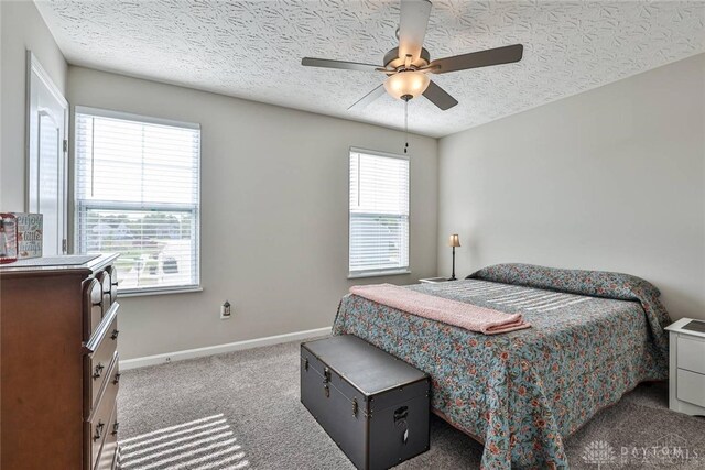bedroom featuring a ceiling fan, baseboards, carpet floors, and a textured ceiling
