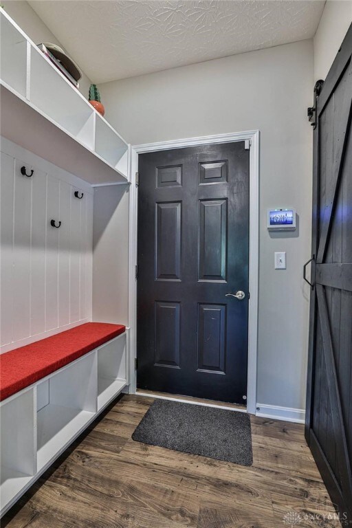 mudroom with baseboards, a textured ceiling, a barn door, and wood finished floors