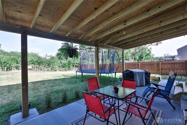 view of patio / terrace featuring outdoor dining area, a trampoline, a grill, and fence