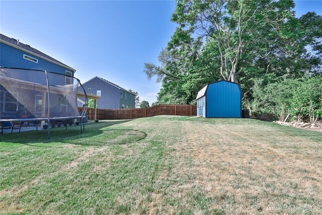 view of yard featuring an outbuilding, a shed, a fenced backyard, and a trampoline