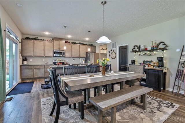 dining space featuring visible vents, a textured ceiling, dark wood-type flooring, and baseboards
