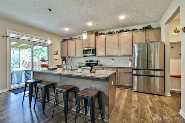 kitchen with dark wood-style floors, stainless steel appliances, tasteful backsplash, and a sink