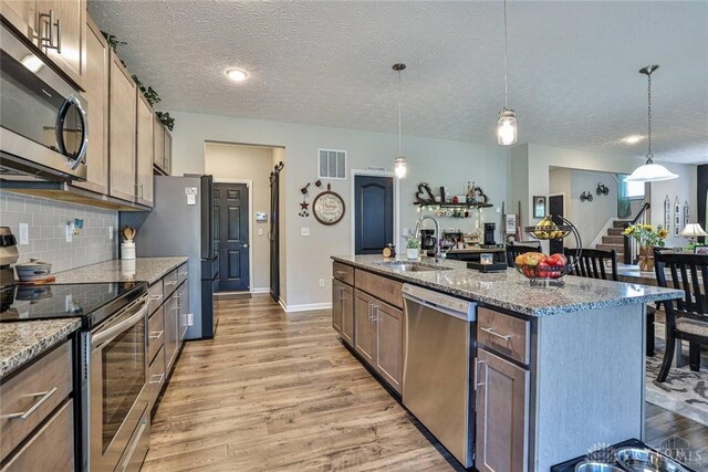kitchen featuring tasteful backsplash, visible vents, appliances with stainless steel finishes, light wood-style floors, and a sink