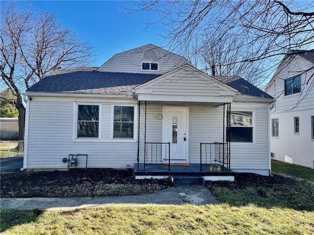 bungalow-style house featuring covered porch, roof with shingles, and a front lawn