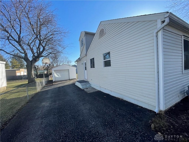 view of side of home with an outbuilding, driveway, a garage, and fence