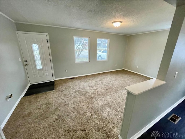 carpeted entrance foyer with visible vents, baseboards, and a textured ceiling