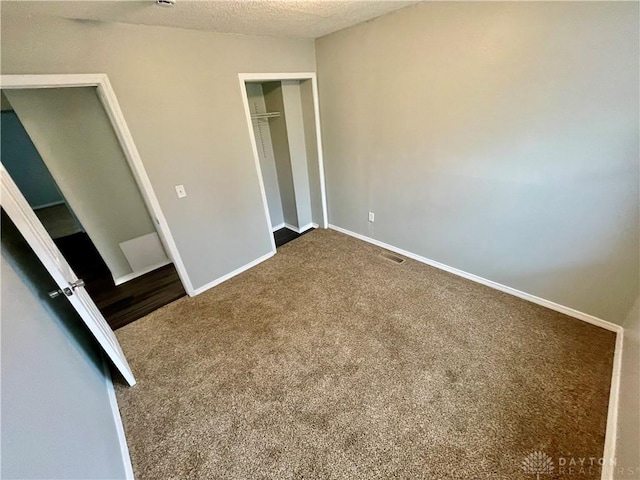 unfurnished bedroom featuring visible vents, a textured ceiling, a closet, carpet flooring, and baseboards