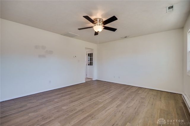 unfurnished room with wood finished floors, visible vents, baseboard heating, and ceiling fan