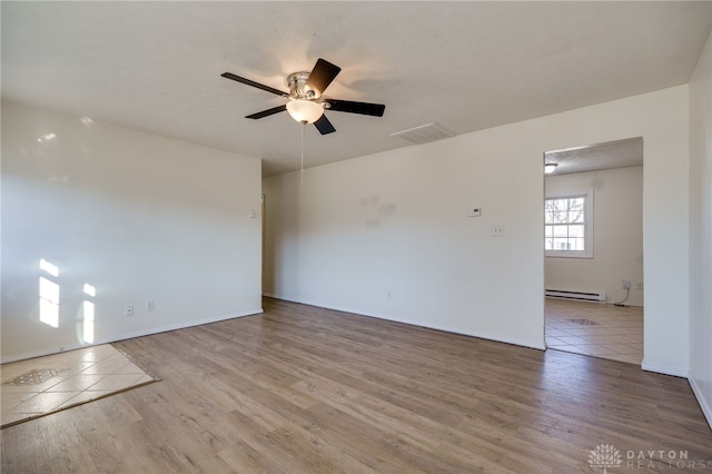 spare room with a ceiling fan, wood finished floors, visible vents, and baseboard heating