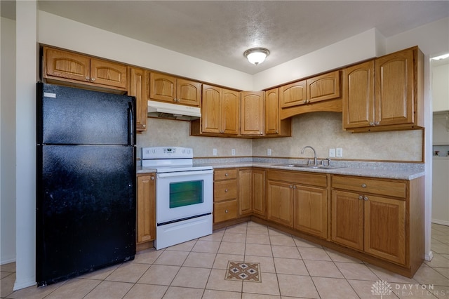 kitchen with electric stove, under cabinet range hood, a sink, freestanding refrigerator, and light countertops