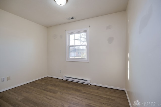 unfurnished room with baseboards, wood finished floors, visible vents, and a baseboard radiator