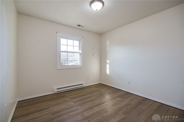 spare room with a baseboard heating unit, visible vents, dark wood-style flooring, and baseboards