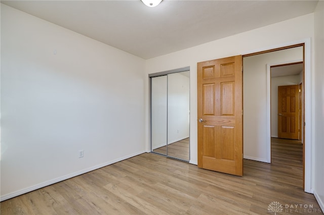 unfurnished bedroom with light wood finished floors, baseboards, and a closet