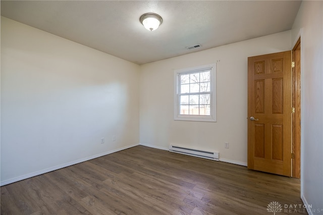 spare room featuring a baseboard radiator, baseboards, visible vents, and wood finished floors