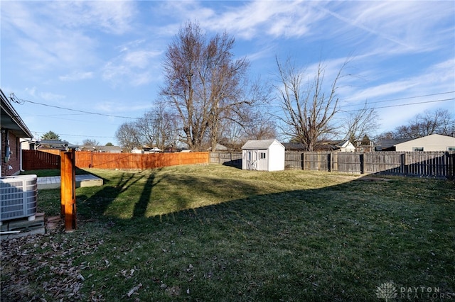 view of yard featuring central air condition unit, a fenced backyard, a storage shed, and an outdoor structure