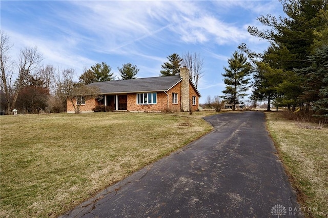 view of front of property with driveway, a chimney, and a front yard