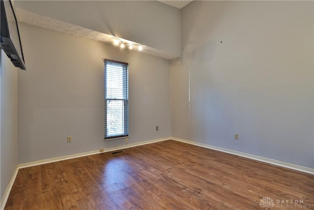 unfurnished room with visible vents, baseboards, and wood finished floors