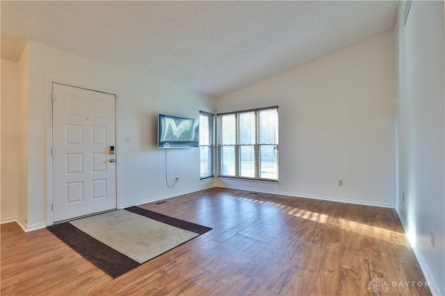 foyer entrance featuring vaulted ceiling, wood finished floors, baseboards, and a textured ceiling