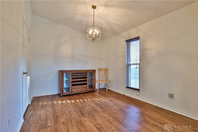 interior space with a notable chandelier, baseboards, and wood finished floors