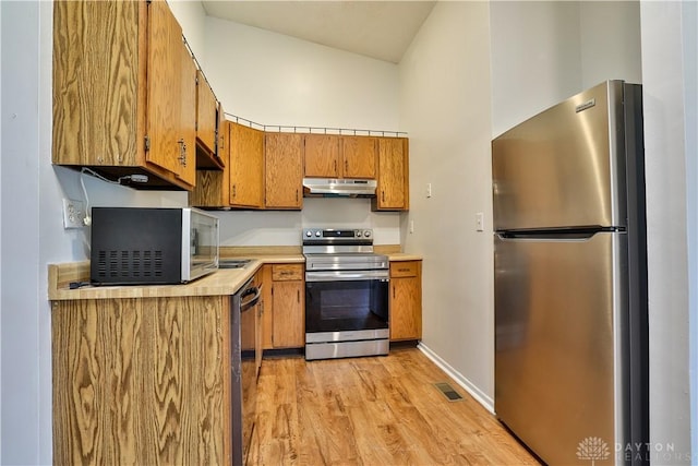 kitchen featuring visible vents, under cabinet range hood, light countertops, appliances with stainless steel finishes, and brown cabinetry