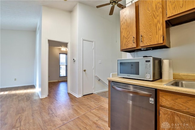 kitchen with dishwasher, light countertops, white microwave, and brown cabinets