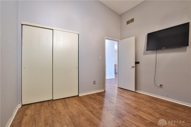 unfurnished bedroom with a closet, visible vents, baseboards, and wood finished floors