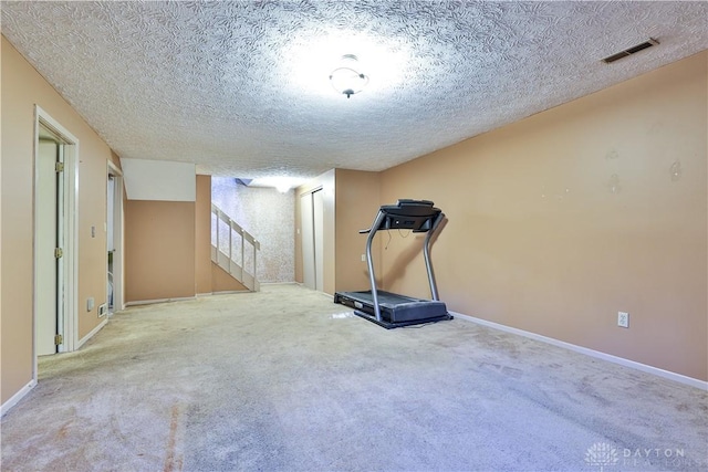 workout area featuring baseboards, visible vents, a textured ceiling, and carpet