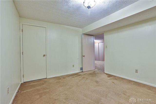 empty room with carpet, baseboards, and a textured ceiling