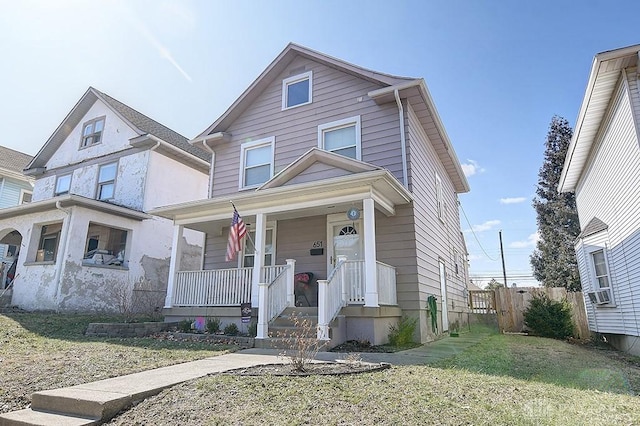 view of front of home with covered porch, a front lawn, and fence