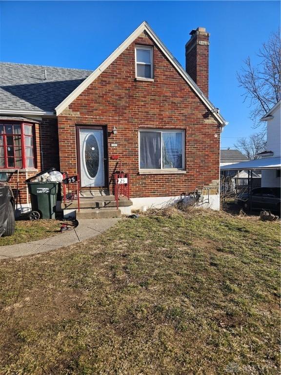 rear view of property with a yard, brick siding, and a chimney