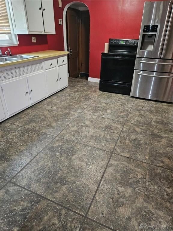 25 Redwood Ave, Dayton, OH 45405 - kitchen featuring a sink, black electric range oven, stainless steel fridge, white cabinets, and arched walkways
